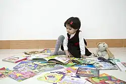 یک دختر بچه در حال خواندن کتابهای رده کودکان