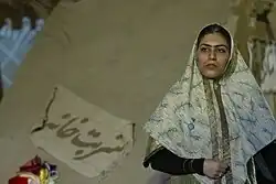 عکس یک زن بازیگر تئاتر که یک روسری به سبک زنان ایران قدیم به سر دارد