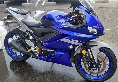 A blue sports motorcycle facing to the right in a parking lot