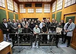 استاد تورج مهرزادیان نشسته بر روی صندلی در وسط، در کنار استاد سعید مظفری و مریم جلینی،  با حضور ظفر گرایی، افشین زی‌نوری، نازنین یاری، حسن کاخی و دیگران در پشت صحنه دوبله مجموعه های نوروزی تلویزیون در استودیو صدا و سیما در اسفند 1397