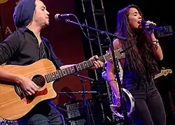 A man and a woman singing together with the man playing guitar
