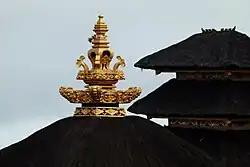 یک کمونچاک بالیایی در بالای یک سقف کاهگلی از یک غرفه معبد بالیایی.