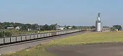 Cluster of houses seen over railroad tracks occupied by train; metal بالابر غله