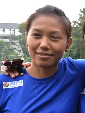 Laishram smiling hard at the camera in a blue jersey.