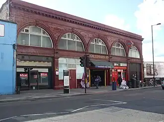 A red-bricked building with "CALEDONIAN RD." in gold letters and a blue sign reading "CALEDONIAN ROAD STATION" in white letters below