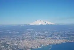 نمای هوایی از کلان‌شهر کاتانیا. قله در دوردست، کوه اتنا است.