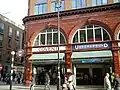 A red-bricked building with a white sign reading "COVENT" in blue letters and a blue sign reading "UNDERGROUND" in white letters under a white sky