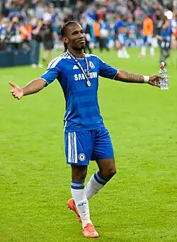 A black man wearing a long-sleeved red-and-white-striped football jersey and white shorts with a number 34 on the left leg.