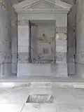 طاقچه با سقف شیبدار در داخل اتاق رو به روی ورودی، که محل مجسمهٔ مهر بوده است.برای خارج ساختن آب بارانی که از طریق نورگیر به داخل می‌ریزد آبراهی مستطیل شکل در کف اتاق تعبیه شده که با مجرایی به قطر پنج سانتیمتر آب باران را از سمت جنوبی سکو به بیرون هدایت می‌کند.