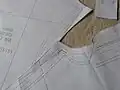 خیاط الگو را با جوهر قرمز درجه بندی (سایزبندی) می‌کند تا با اندازه‌گیری‌های متناسب با شخصی که لباس را می‌پوشد مطابقت داشته باشد.
