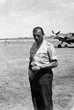 The head and shoulders of a young man, shown in semi-profile. He wears a shirt with an Iron Cross displayed at the front of his shirt collar.