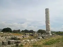 A free standing column and ruins around