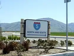 Highway directional sign in Wheeler Ridge, with Tehachapi Mountains beyond