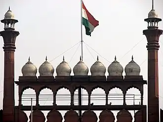 The national flag of India hoisted on a wall adorned with domes and minarets