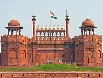 The national flag of India hoisted on a wall adorned with domes and minarets.