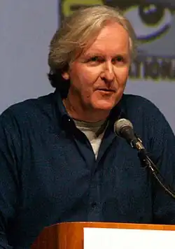 Photo of a grey-haired man wearing a black shirt speaking into a microphone.