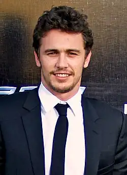 James Franco dressed in a suit, is smiling towards the camera.