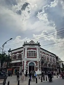 Exterior of colonial building with people walking around.