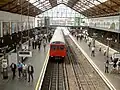 The interior of a building with windows on the ceiling and a railway track running from the background to the foreground in the centre