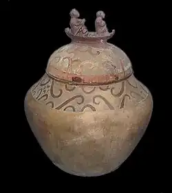 کوزه‌ای با درپوش تزئین‌شده با دو نفر روی یک قایق