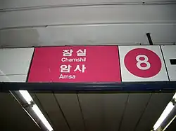 An overhead sign in rose and white with a big number 8 and the words Chamshil and Amsa in hangul and Latin script.