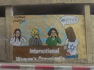 یک این اثر دیواری در اسرائیل که سازمان‌های بین‌المللی زنان و جنبش MeToo# را به دلیل نادیده گرفتن جنایاتی چون تجاوز و خشونت جنسی در حمله ۷ اکتبر توسط حماس را مورد انتقاد قرار داده است.