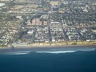 Aerial view shows: Moonlight Beach on the left, parallel with the shore is Historic Coast Highway 101, also parallel but further inland is Interstate 5 in California