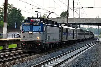 Silver and blue locomotive with passenger cars passing through a station
