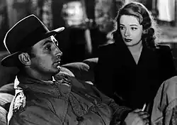 A black and white screenshot of Robert Mitchum on the left and Jane Greer on the right in the film Out of the Past