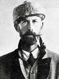 عکس سیاهوسفید مردی با کلاه که سیگاری در دهان دارد.