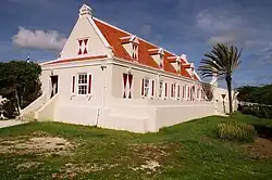 White plantation building with red roof, trees around