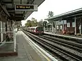 Looking east towards Chigwell and Hainault. Train arrives on a Woodford-bound service