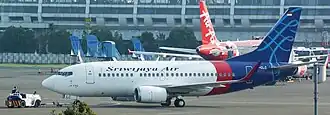 A shot of the plane pushing back, seen from the left side. Behind it is an Air Asia parked at its gate.