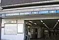 A brown-bricked building with a rectangular, light blue sign reading "STOCKWELL STATION" in white letters all under a light blue sky