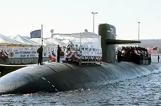 USS Pittsburgh (SSN-720) participates in a dockside ceremony. Note the USN jack waving from the front of the sub.
