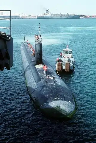 The USS Topeka (SSN-754) prepares to dock with the assistance of a tugboat.