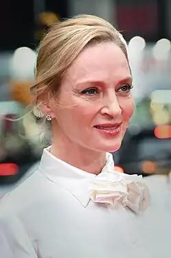 Thurman turning toward the camera, wearing a black coat