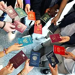 افرادی که در یک دایره ایستادهاند و گذرنامههای کشورهای مختلف را در دست گرفتهاند.