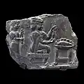 Relief of a woman being fanned by an attendant while she holds what may be a spinning device before a table with a bowl containing a whole fish (700–550 BC)