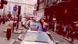 Lipa in a limousine sticking her head out of the sunroof as it drives around Soho, London.