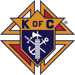 The Knights of Columbus emblem consists of a shield mounted on a Formée cross. Mounted on the shield are a fasces, an anchor, and a dagger.