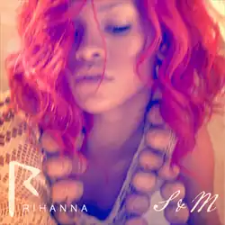 A close-up shot of a woman with red hair and her eyes closed. She is wearing a chunky necklace and a beige top.