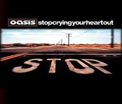 Picture of a desertic road. In the pavement the word "Stop" is painted in capital white letters. Above it, Oasis's stylised logo and "Stop Crying Your Heart Out", written in lowercase white letters and without spaces, appear.