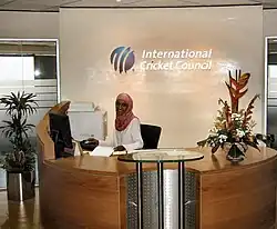 دختری جوان در حالی که پشت یک میز پذیرش کار میکند به دوربین لبخند میزند