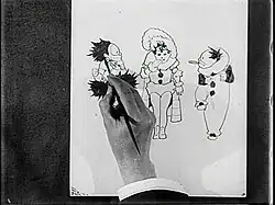 Film still of a hand sketching three cartoon characters