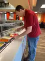 A customer gets food from a buffet in a restaurant.