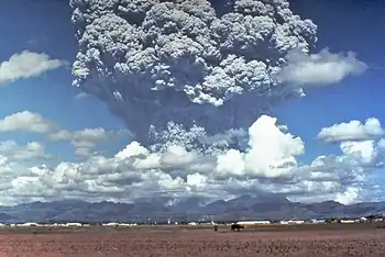 A tower of grey ash erupts above a mountain